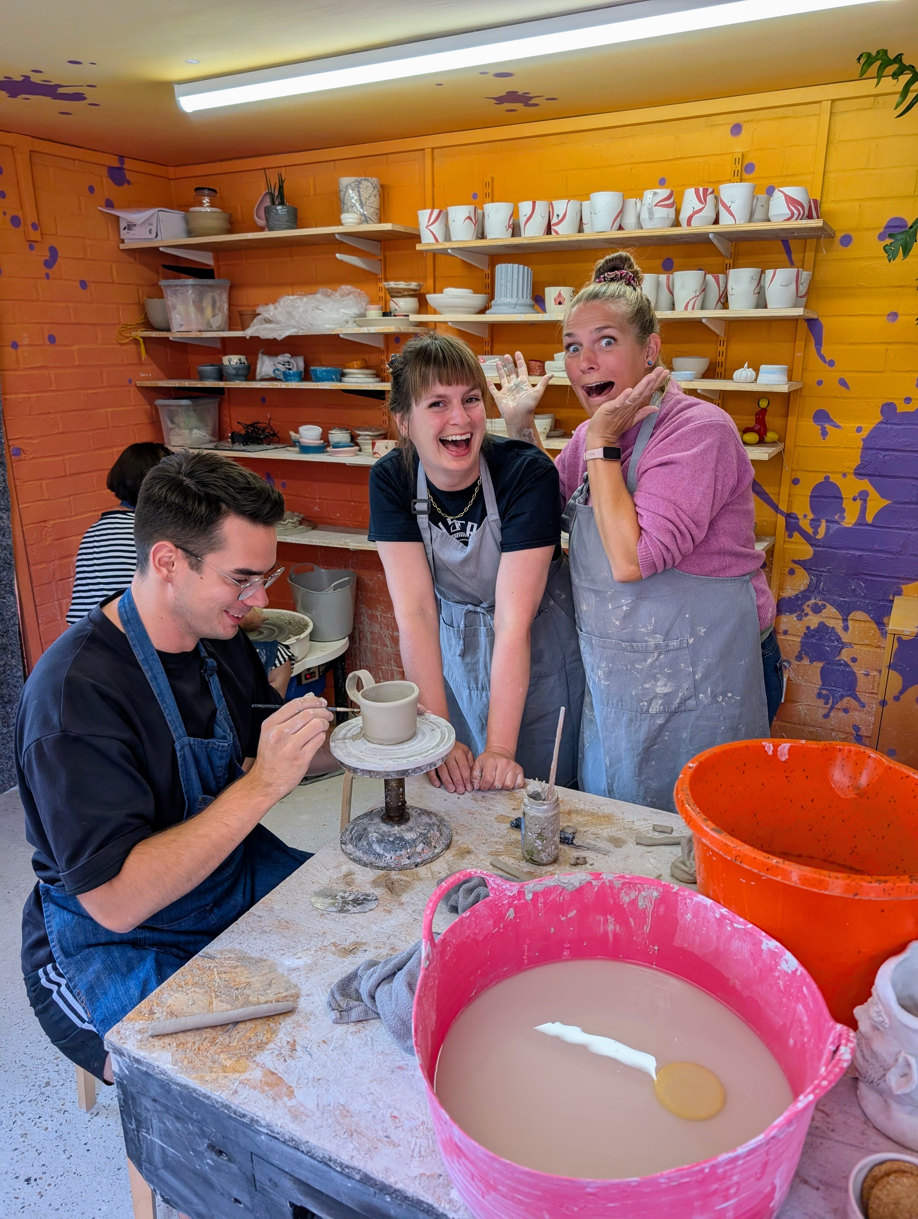 Group of students learning together at the pottery wheel at Ceramic Love studio