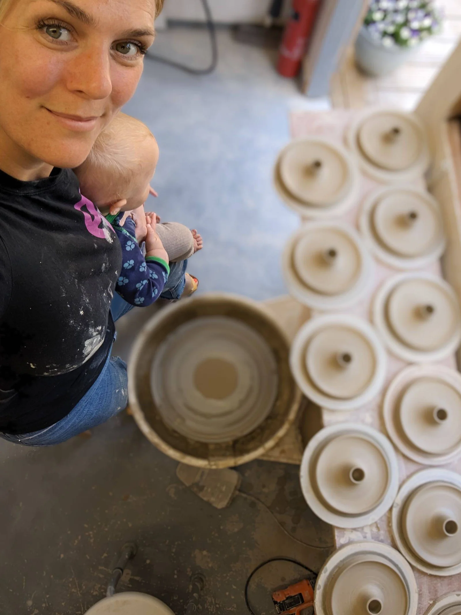 Amanda in the studio beside a row of freshly thrown pieces