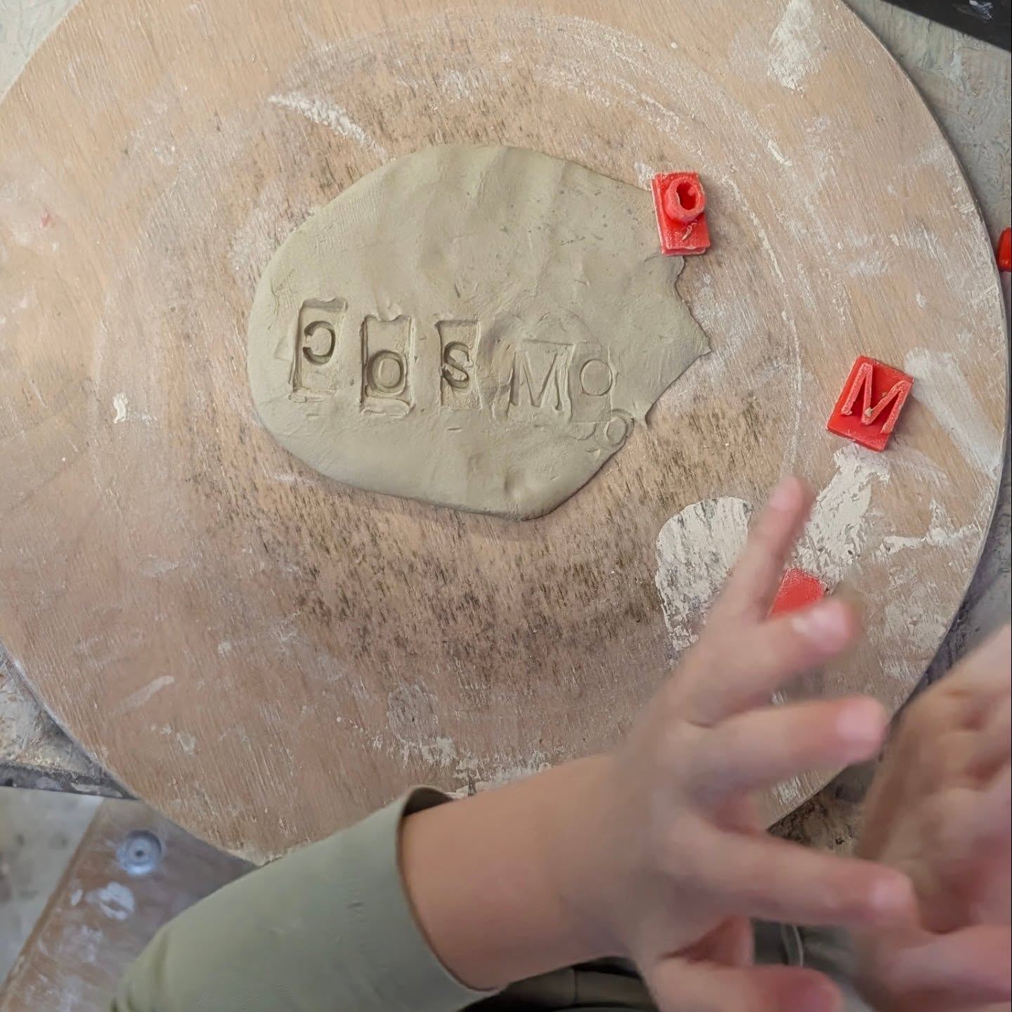 Child stamping letters into clay at a pottery workshop